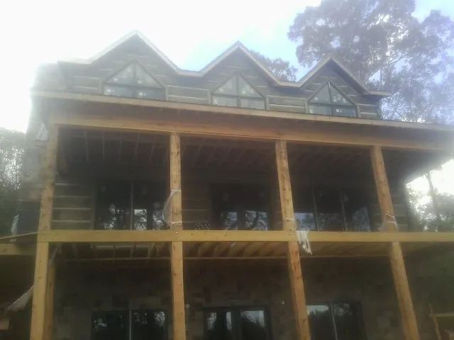 Dormers and porch framing on a large log home under construction — Roof Coating work by our crew in Somerset